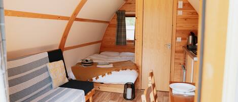 Una habitación acogedora y compacta con cama, una mesita y un banco.