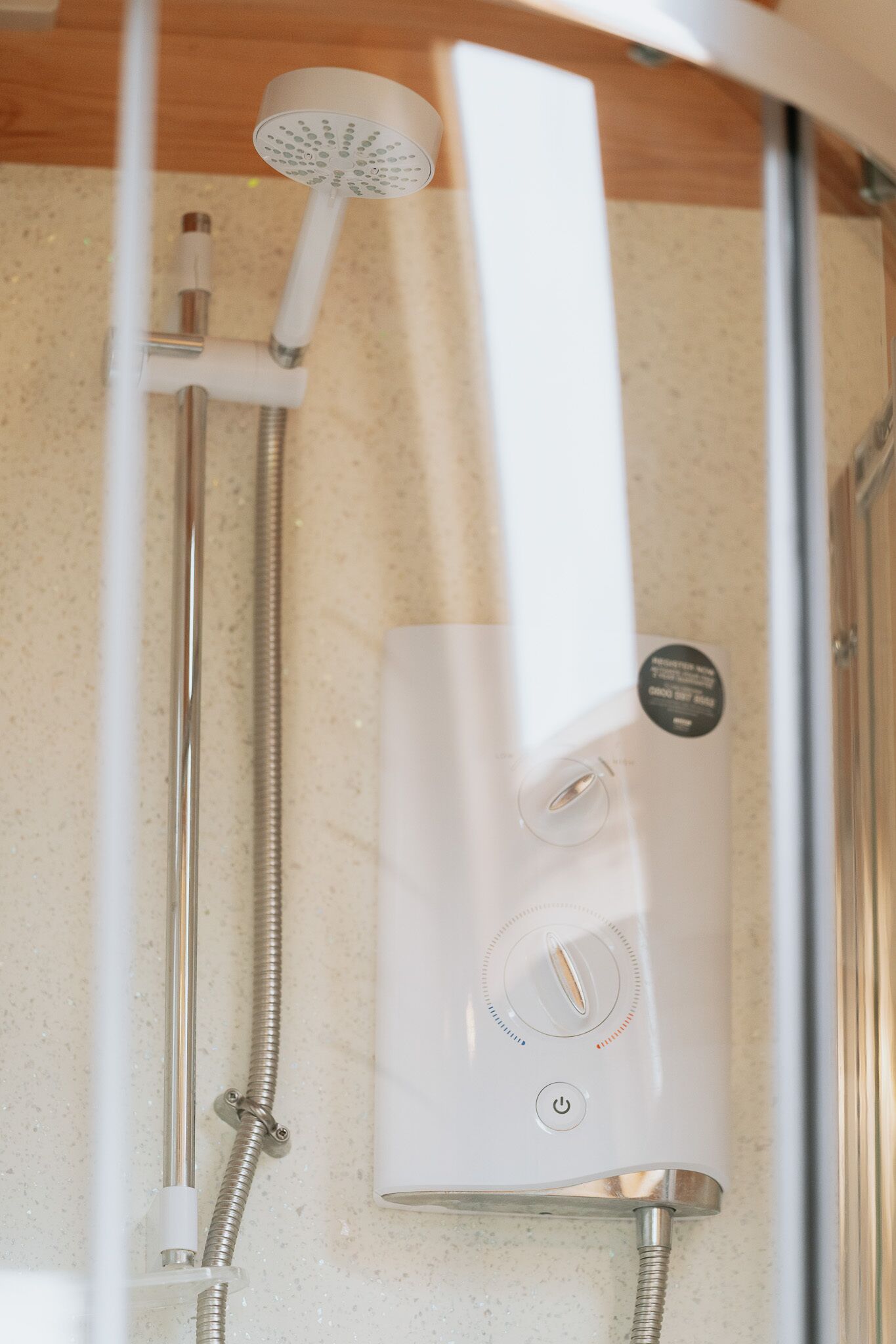 Een moderne douche met een handdouche en bedieningspaneel.