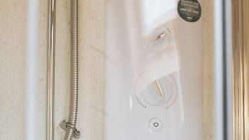 Een moderne douche met een handdouche en bedieningspaneel.