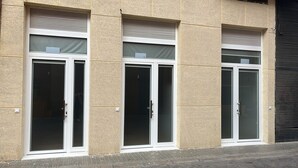 Eine Gebäudefassade mit drei nummerierten Türen, jede mit einer Glasscheibe und einem Griff.