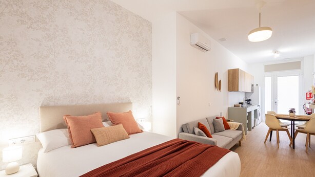 Ein modernes Hotelzimmer mit einem großen Bett, einer Sitzecke, einem Essbereich und einer Küchenzeile.