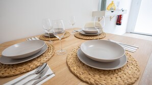 A dining table set with plates, glasses, and cutlery, with a woven placemat underneath each plate.