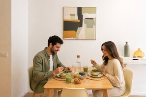 Una mesa de comedor con comida, una botella y un bol de fruta.