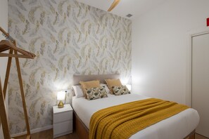 Un dormitorio ordenado con cama, mesitas de noche y armario.