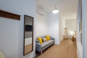 Ein modernes Wohnzimmer mit grauem Sofa, Holzboden und einem großen Spiegel.