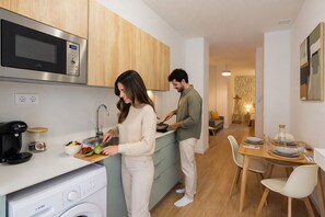 A modern kitchen with a Bosch coffee maker, a microwave, and a sink. There's a dining area with a table set for two.