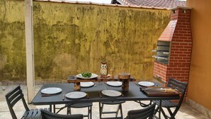 Una zona d'exterior per dinar amb una taula preparada per a quatre persones, envoltada de cadires.