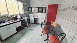 Una cuina amb armaris blancs, una porta vermella i una zona de menjador amb caires.