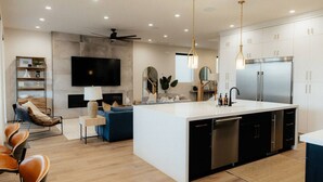 A modern kitchen with a central island, stainless steel appliances, and a dining area with chairs. - Sleeps 26! Private Pool, Hot Tub, Theater, & More! (Hurricane)