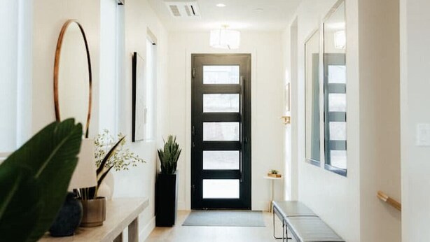 A hallway with a wooden bench, a potted plant, and a black-framed door. - Sleeps 26! Private Pool, Hot Tub, Theater, & More! (Hurricane)