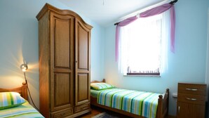 A bedroom with two single beds, a wardrobe, a window with curtains, and a nightstand with a lamp. - Apartment With Scenic View (Porec)