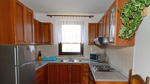 A compact kitchen with wooden cabinets, a stainless steel refrigerator, a microwave, and a gas stove. - Apartment With Scenic View (Porec)