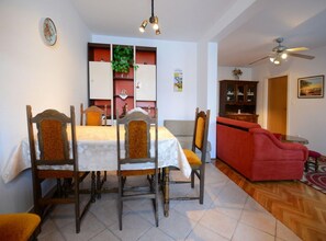 A dining area with a table and chairs, a red sofa, a ceiling fan, and a cabinet with a plant. - Apartment With Scenic View (Porec)
