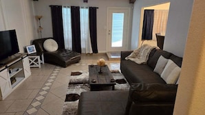 A living room with a sofa, armchair, coffee table, and a television. - Charming 3-bedroom house in lovely McAllen with AC, WiFi, Swimming pool. (McAllen)