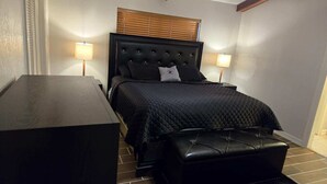 A bedroom with a bed, bedside lamps, a wooden nightstand, and a bench. - Charming 3-bedroom house in lovely McAllen with AC, WiFi, Swimming pool. (McAllen)