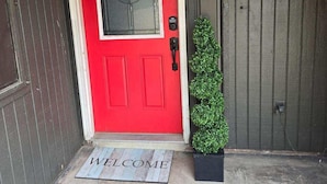 A red door with a glass panel and a small potted plant beside it. - Charming 3-bedroom house in lovely McAllen with AC, WiFi, Swimming pool. (McAllen)