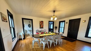 A dining area with a wooden floor, white chairs, a central table, and a ceiling light fixture. - Charming 4 Bed, 2.5 Bath home minutes from Madison perfect for any occasion. (McFarland)