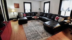 A living room with a black leather sectional sofa, a small round coffee table, a lamp, and a painting on the wall. - Charming 4 Bed, 2.5 Bath home minutes from Madison perfect for any occasion. (McFarland)