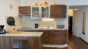 A modern kitchen with wooden cabinets, a built-in oven, and a coffee maker. - Charming Apartment in Nature (Zagreb)