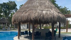Una piscina amb un pabelló de palla i gandules.