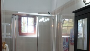 Un baño con ducha de vidrio, inodoro, lavamanos y espejo.