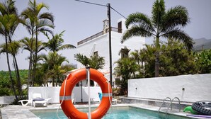 A swimming pool with a lifebuoy, surrounded by palm trees and a white building. - Apartment Padres A for 4 People (La Orotava)