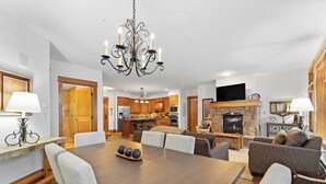 A spacious living area with a dining table, comfortable seating, a fireplace, and a kitchen in the background. - Le3012-2 (Keystone)