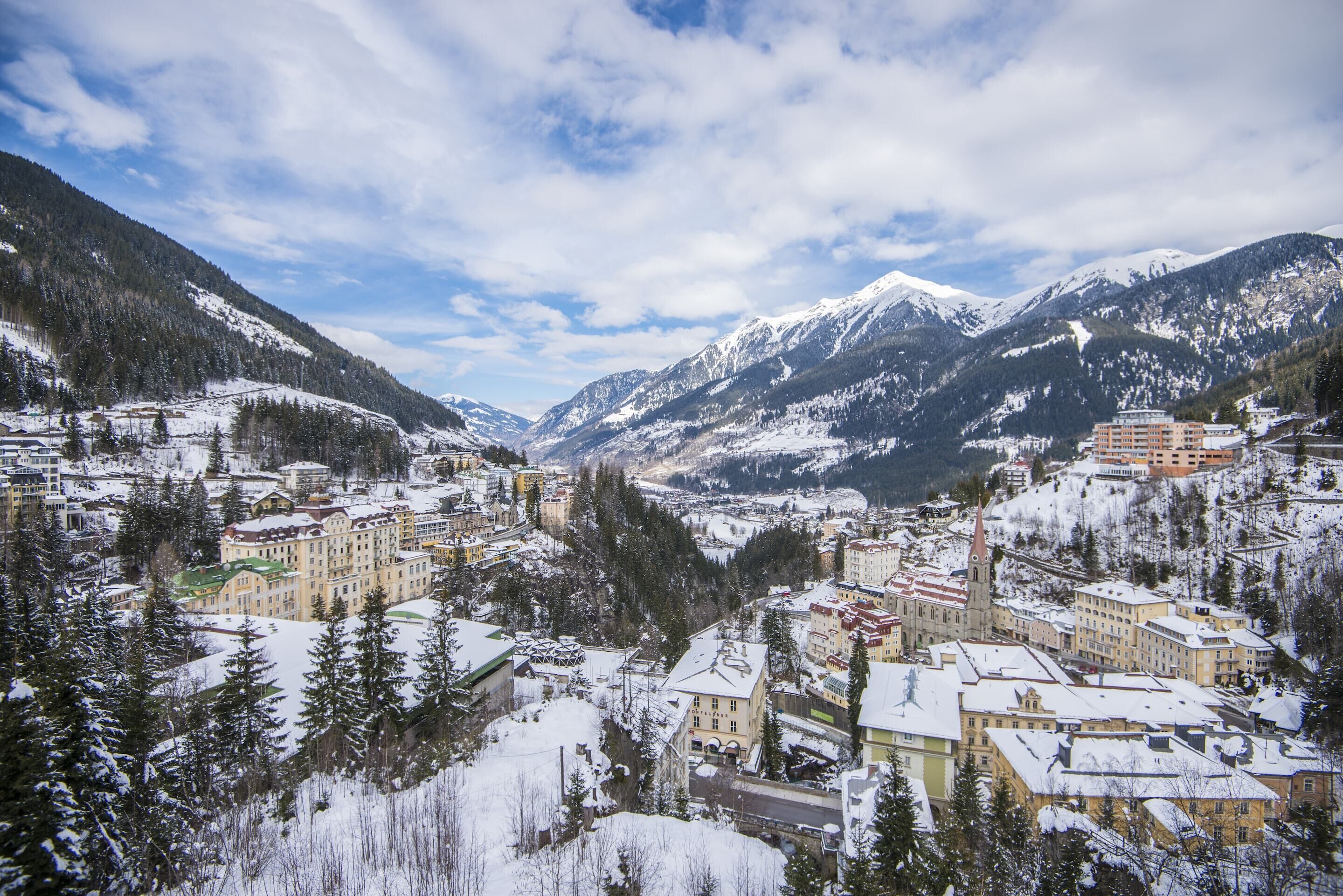 A snow-covered town with buildings, a church, and mountains in the background.