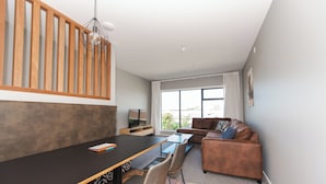 Una sala moderna con comedor, sofá y televisor.