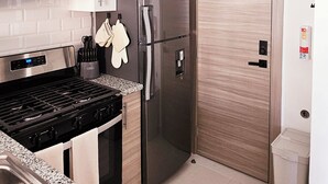 Una cocina moderna con estufa de acero inoxidable, refrigerador y puerta de madera.