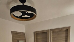 Un dormitorio con una cama, un armario de madera y un ventilador de techo.