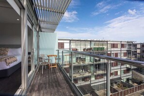 Un apartamento moderno con balcón, barandillas de vidrio y vistas a otros edificios.