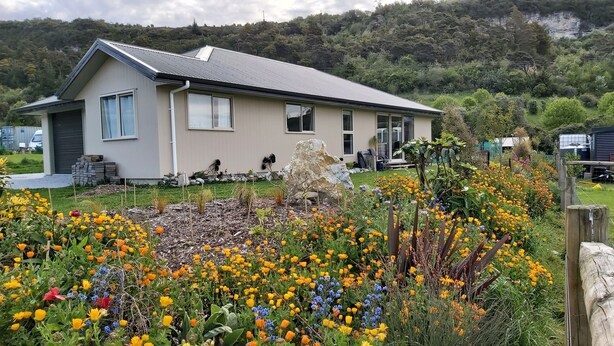 A modern house with a sloped roof, large windows, and a garden with a variety of flowers. - Ruru at Ligar Bay (Ligar Bay)
