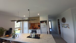 A modern kitchen with white cabinets, a marble countertop, and a hanging light fixture. - Ruru at Ligar Bay (Ligar Bay)