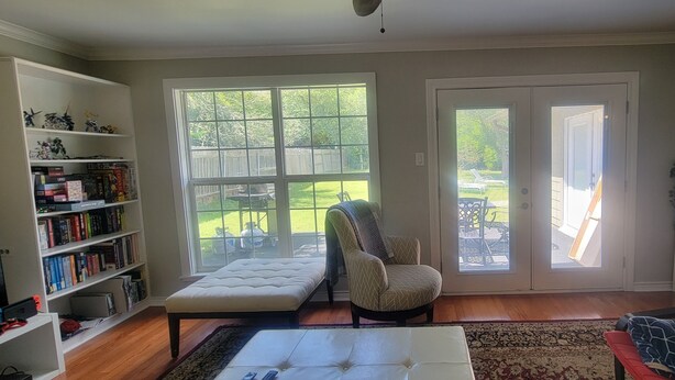 Una sala de estar con sofá, sillón, otoman y estantería.