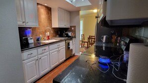 Una cocina compacta con armarios blancos, una encimera negra y un horno empotrado.