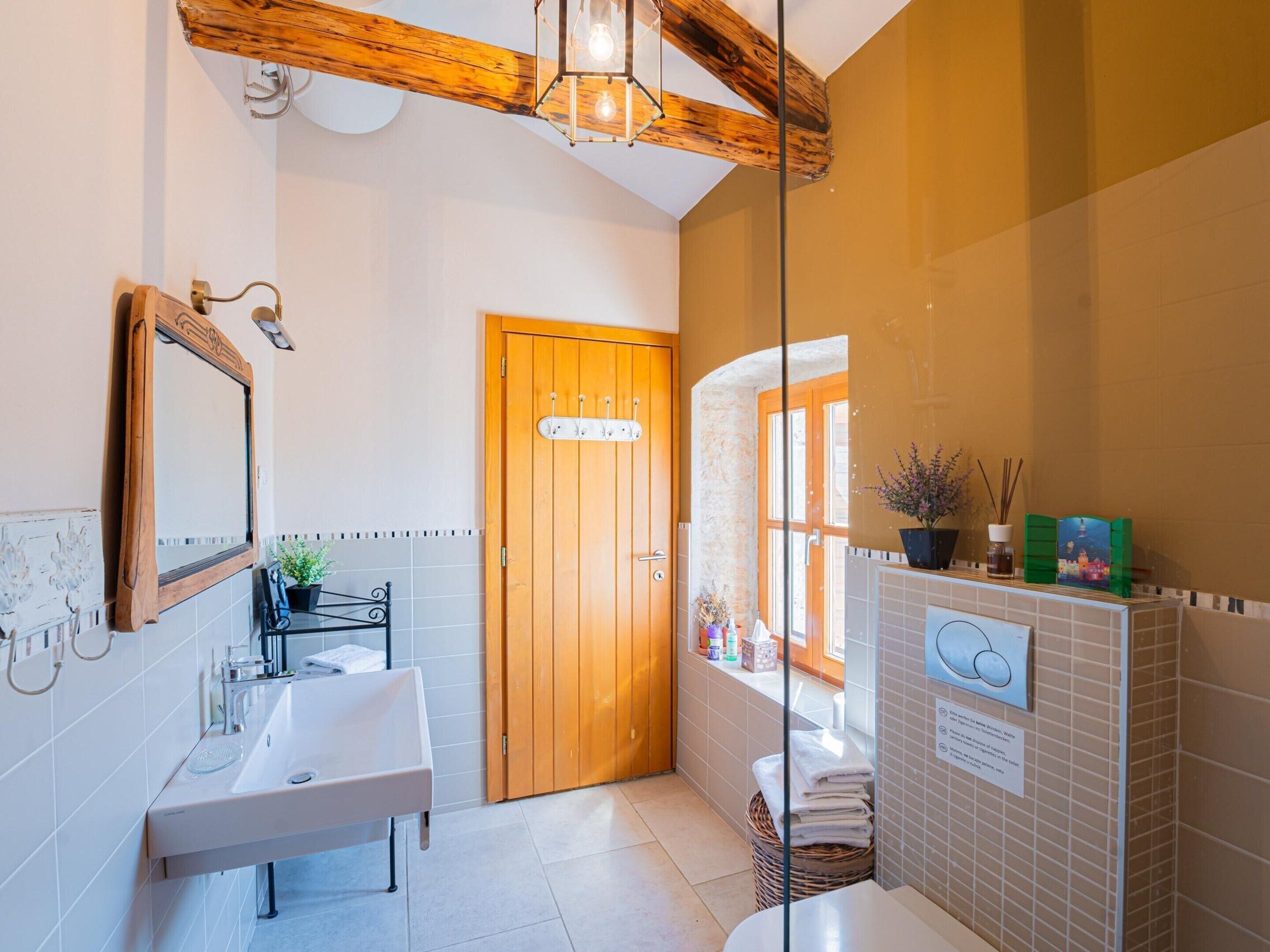 A bathroom with a wooden door, a sink, a mirror, and a window.