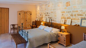 A bedroom with a stone wall, a bed with a headboard, a wooden bench, a wooden wardrobe, and a chair. - Villa Benka With View (Tinjan)