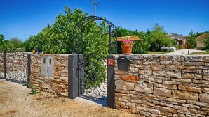 A stone wall with a metal gate, a mailbox, and a potted plant. - Villa Benka With View (Tinjan)