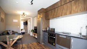 Een moderne keuken met houten kastjes, roestvrijstalen apparatuur en een glazen eettafel.