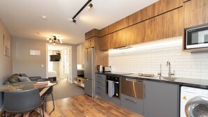 Een moderne keuken met houten kastjes, roestvrijstalen apparatuur, een inbouwoven en een wasmachine.