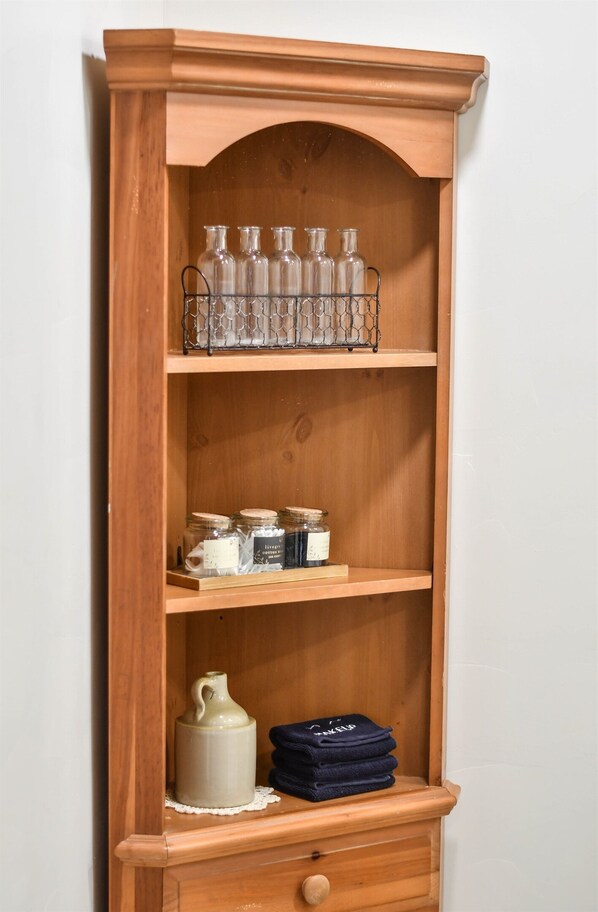 Un mueble de madera con botellas, frascos y toallas dobladas.