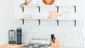 A kitchen with a stove, a coffee maker, and a knife block on the counter.