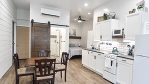 A modern kitchen with white cabinets, a wooden dining table, and a ceiling fan. - Anniversary Suite with a stunning country setting! (Sugarcreek)