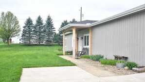 A residential building with a covered porch, a concrete driveway, and a well-maintained lawn. - Anniversary Suite with a stunning country setting! (Sugarcreek)