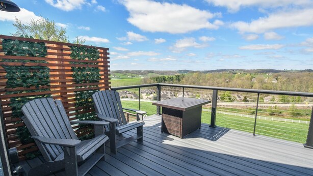 A deck with two Adirondack chairs, a small table, and a wooden fence with greenery. - Luxury Honeymoon Suite Amazing Views Amish Country (Walnut Creek)