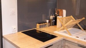 A modern kitchen with a built-in stove, wooden cabinets, and a stainless steel range hood. - 3 rooms flat with garden next to the train station (Nevers)