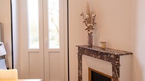 A room with a fireplace, a vase with dried flowers, and a candle on a mantelpiece. - 3 rooms flat with garden next to the train station (Nevers)