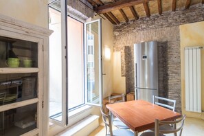 A kitchen with a wooden table, chairs, a refrigerator, and a window with a view. - Charming Luxury Trastevere Apartment (Roma)