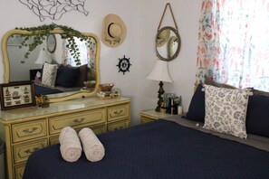 A neatly arranged bedroom with a bed, dresser, and two bedside tables.